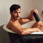 Arcwave Pow Silicone Stroker, Black, Stroker in Hand of Male Model in White Bathtub